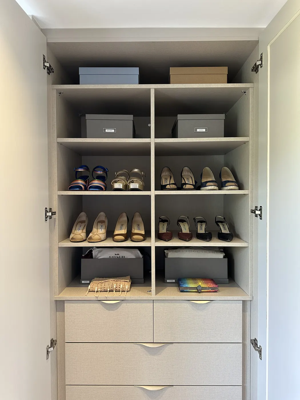 Shoe cupboard with pairs lined up on shelves and labelled boxes above