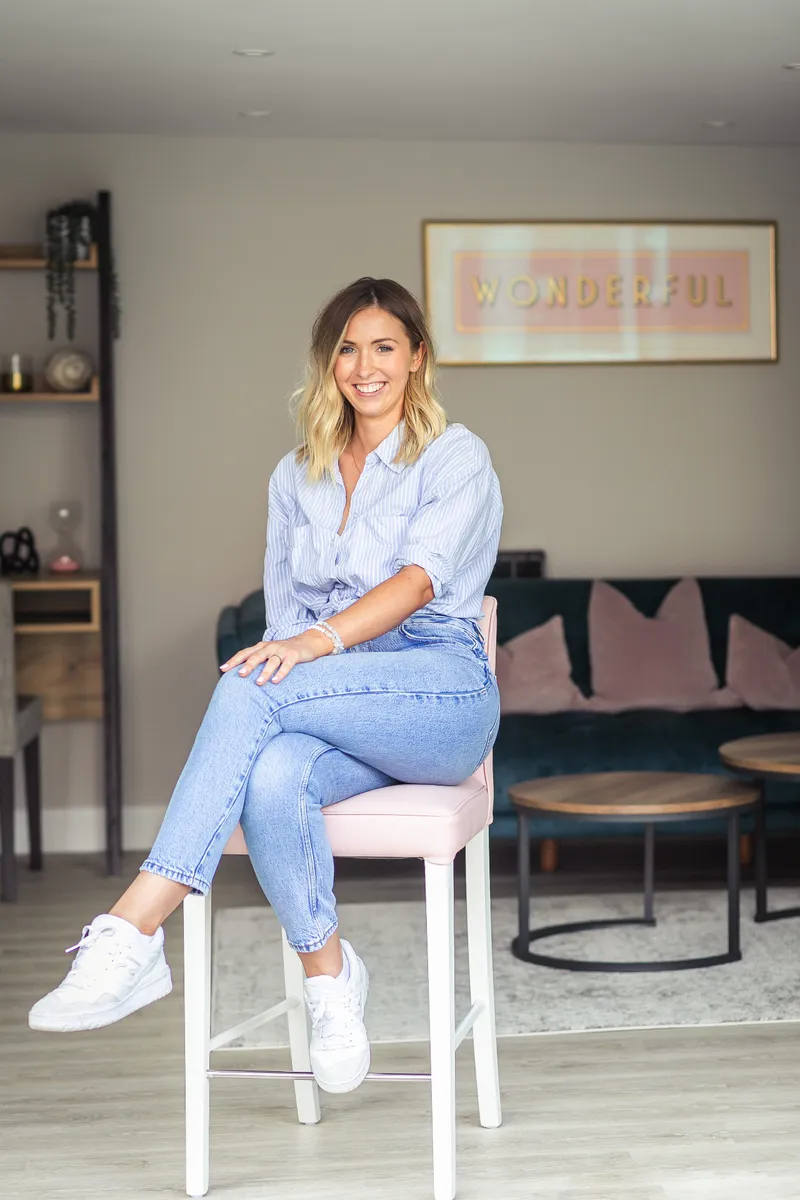 Ruth Lawrence sitting on a pink bar stool in a calm living room