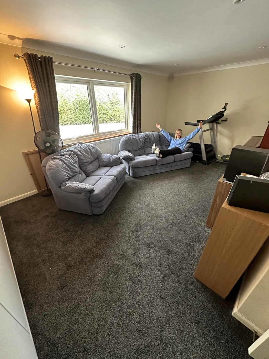 The same living room after organising, with a clear floor and Ruth sitting on one of two sofas
