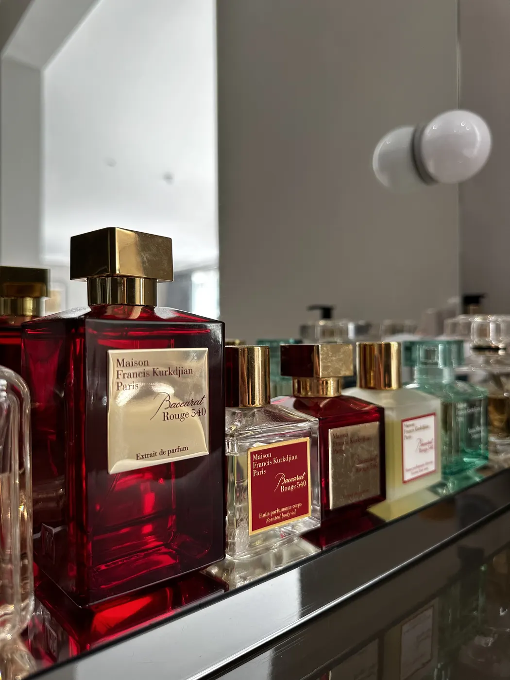Perfume bottles lined up on a mirrored dressing shelf