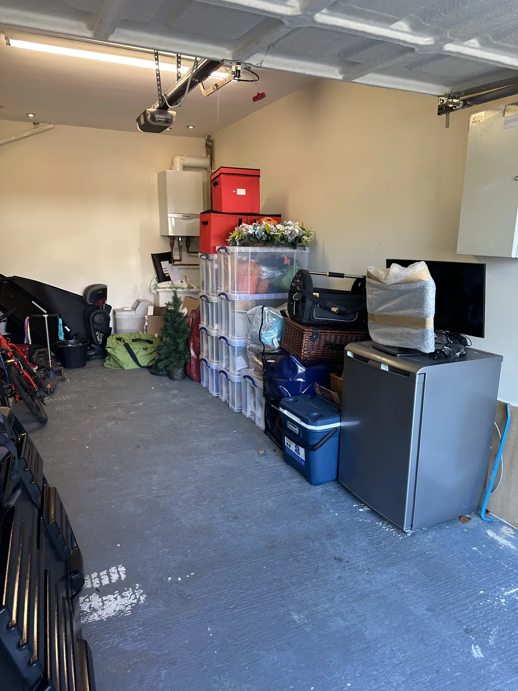 Garage after: floor clear, storage boxes stacked neatly along one wall